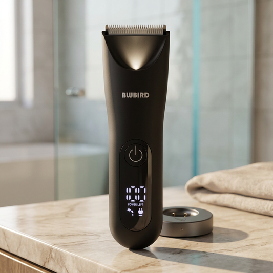 Blubird Trim Reaper no-nick body trimmer on a warm-neutral marble bathroom countertop with charging dock in editorial morning light, BLUBIRD wordmark visible on the device body